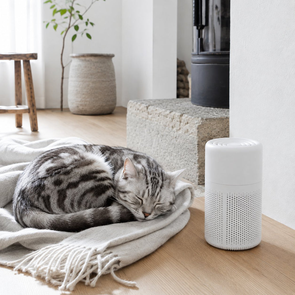 White cylindrical HEPA air purifier with perforated vents, shown beside a sleeping cat at home (view 2)