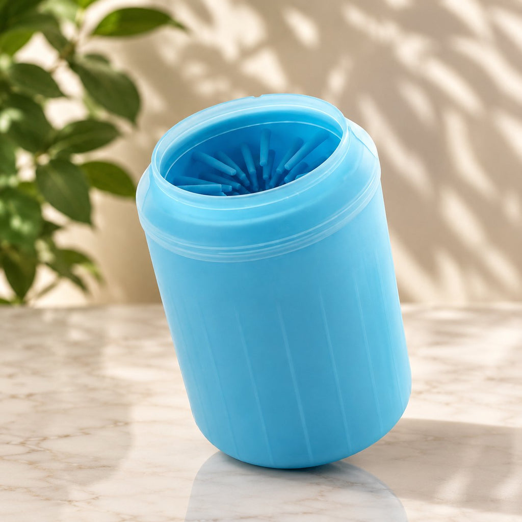 Blue silicone dog paw cleaner cup held in a hand next to a sitting Shiba Inu dog (view 2)
