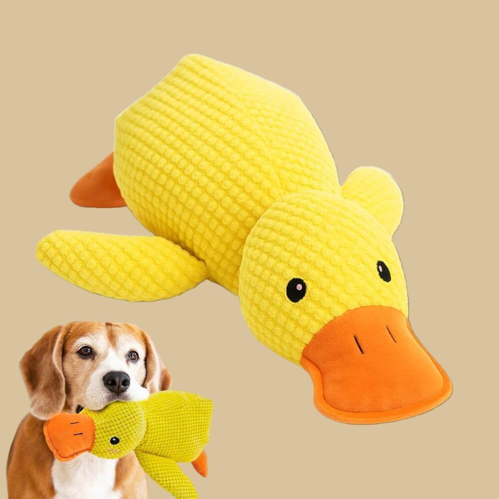 Yellow plush duck dog toy with orange bill and feet, textured fabric, lying on a light surface (view 3)