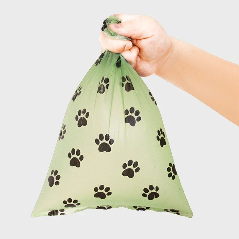 Hand holding a dog waste bag with paw prints