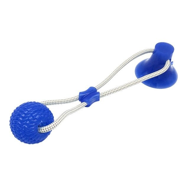 Dog pulling a green suction cup tug toy with textured ball and rope on a smooth floor (view 2)