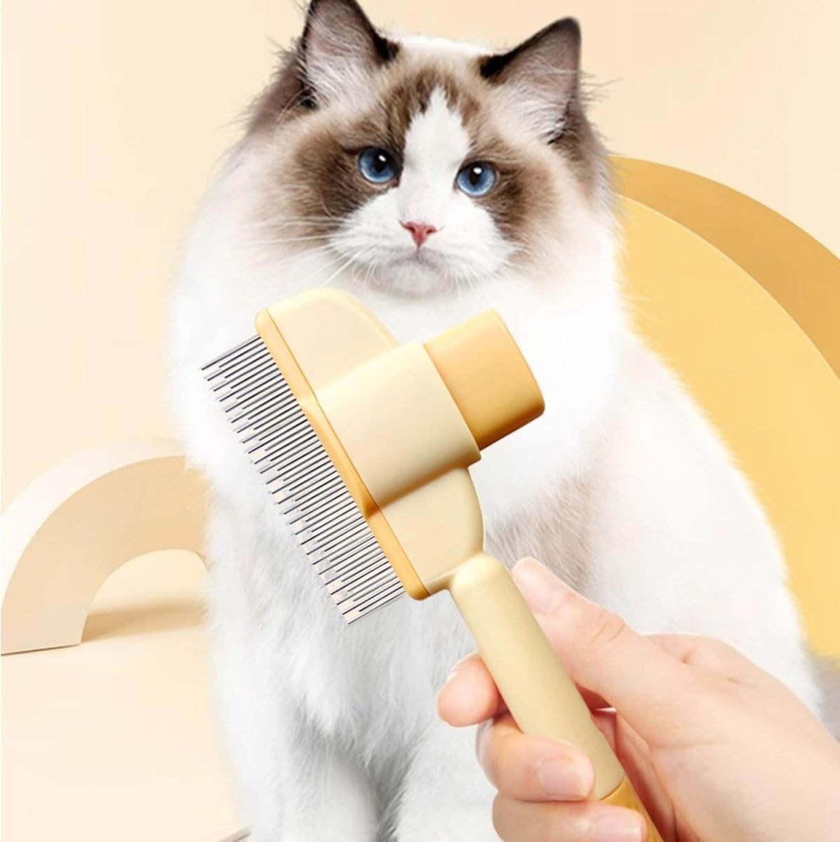 Self-cleaning pet grooming comb with stainless steel teeth and yellow plastic handle held beside a fluffy cat